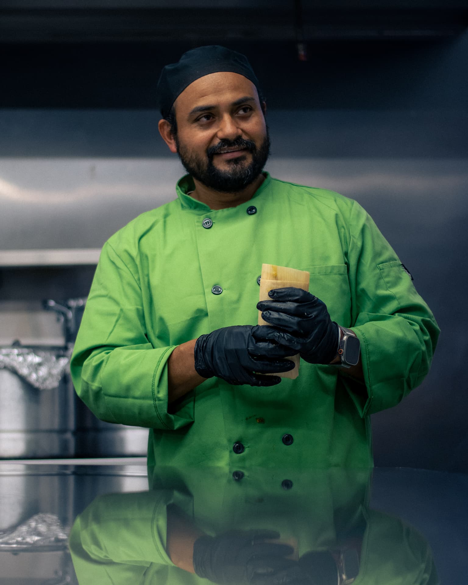Chef Pacheco holding a freshly wrapped tamale in his kitchen